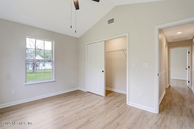 unfurnished bedroom featuring baseboards, visible vents, vaulted ceiling, and light wood finished floors