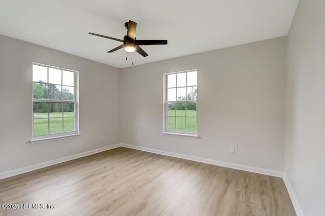 spare room featuring a ceiling fan, plenty of natural light, baseboards, and wood finished floors