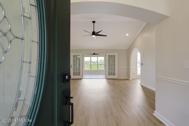 foyer entrance featuring baseboards, wood finished floors, a ceiling fan, arched walkways, and lofted ceiling