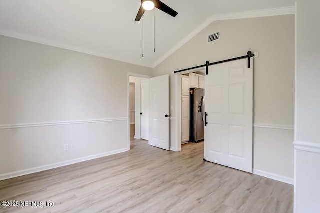 unfurnished bedroom with visible vents, ornamental molding, lofted ceiling, stainless steel refrigerator with ice dispenser, and light wood-style floors