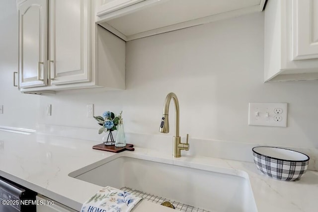 kitchen with white cabinets, a sink, and light stone countertops