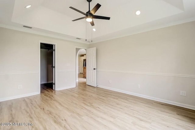 unfurnished bedroom featuring a raised ceiling, light wood-style flooring, baseboards, visible vents, and recessed lighting