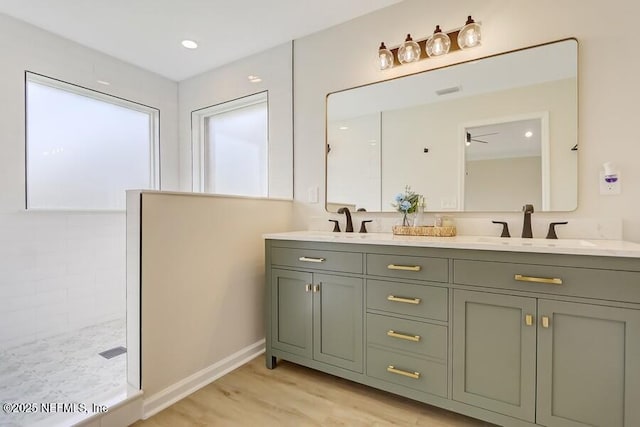 full bath featuring double vanity, a sink, wood finished floors, and a wealth of natural light