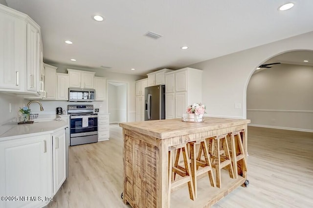 kitchen with light countertops, stainless steel appliances, a sink, arched walkways, and visible vents