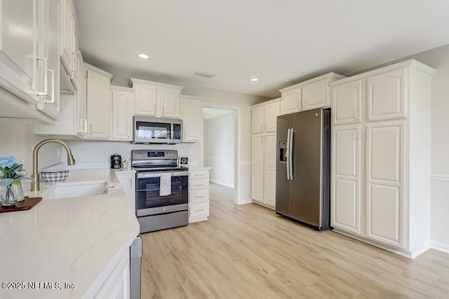 kitchen featuring white cabinetry, light wood-style floors, a sink, and stainless steel appliances