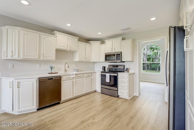 kitchen with white cabinetry, visible vents, stainless steel appliances, and light wood-style floors