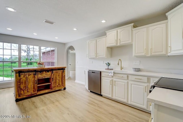 kitchen with white cabinetry, stainless steel dishwasher, a sink, arched walkways, and light wood finished floors