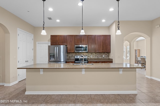 kitchen with backsplash, a sink, stainless steel appliances, visible vents, and arched walkways