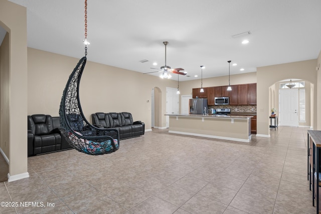 living area featuring a ceiling fan, arched walkways, baseboards, and recessed lighting