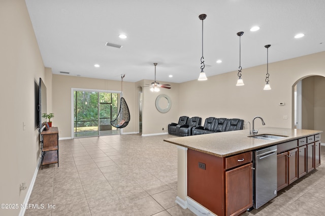 kitchen featuring a ceiling fan, arched walkways, a sink, open floor plan, and pendant lighting
