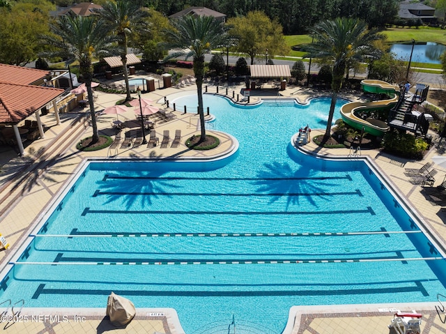 pool featuring fence, a water slide, and a patio area