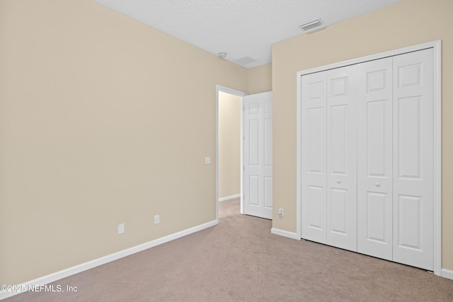 unfurnished bedroom featuring baseboards, a textured ceiling, visible vents, and carpet