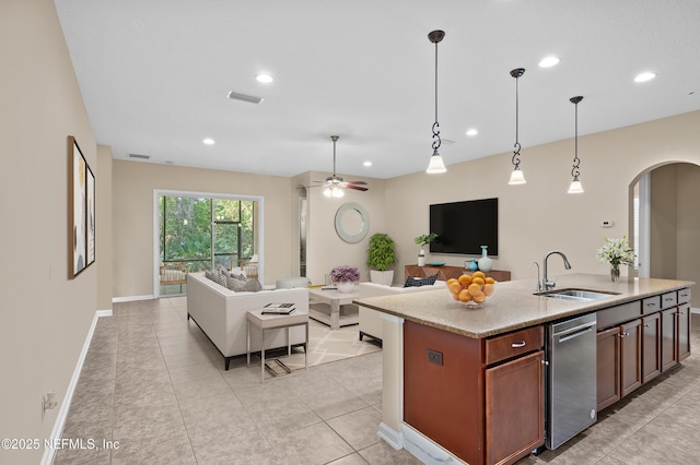 kitchen with a ceiling fan, arched walkways, a sink, open floor plan, and pendant lighting