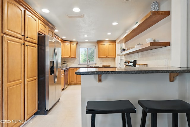 kitchen with open shelves, a breakfast bar area, a peninsula, stainless steel appliances, and decorative backsplash