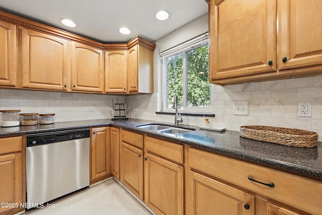 kitchen with recessed lighting, dark stone countertops, stainless steel dishwasher, a sink, and backsplash