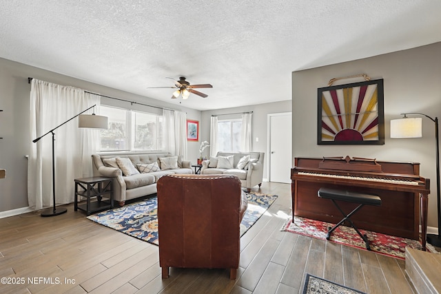 living room featuring baseboards, a textured ceiling, wood finished floors, and a ceiling fan