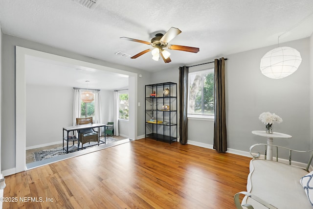 unfurnished room featuring a ceiling fan, plenty of natural light, a textured ceiling, and wood finished floors