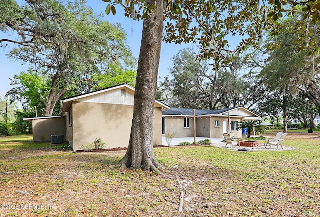 back of house with stucco siding, an outdoor fire pit, central AC, and a patio area