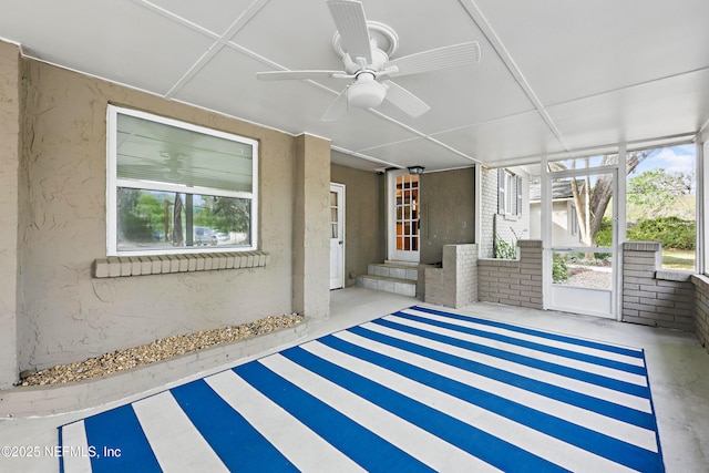 unfurnished sunroom with entry steps, a ceiling fan, and plenty of natural light