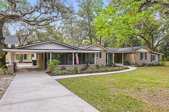 ranch-style house with brick siding, an attached carport, concrete driveway, and a front lawn