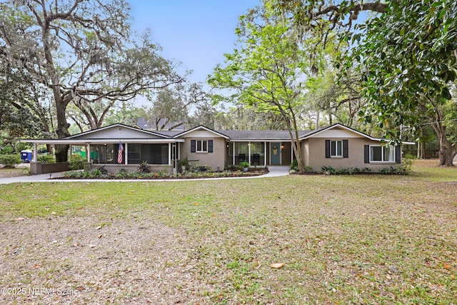 ranch-style home with driveway, a sunroom, a front yard, and a carport