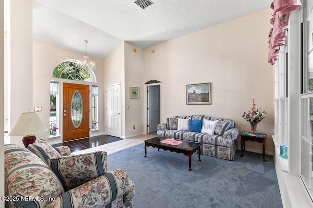 388 Lolly Ln, Saint Johns, FL 32259 - carpeted living area featuring a textured ceiling, visible vents, baseboards, high vaulted ceiling, and a notable chandelier