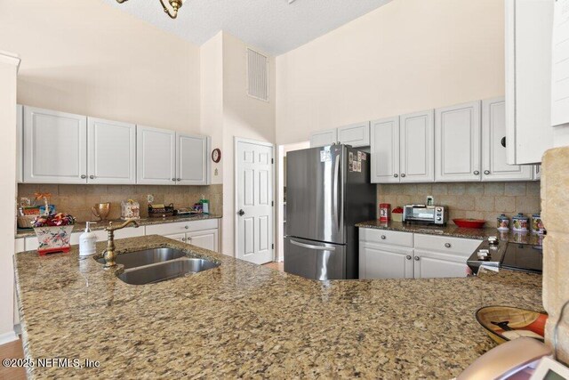 388 Lolly Ln, Saint Johns, FL 32259 - kitchen featuring freestanding refrigerator, visible vents, a sink, and light stone counters