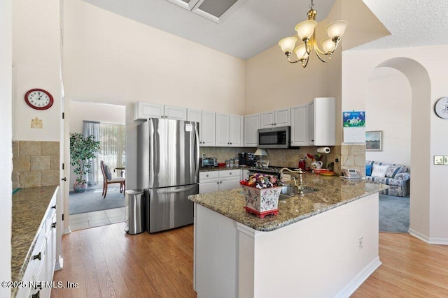 388 Lolly Ln, Saint Johns, FL 32259 - kitchen featuring stainless steel appliances, arched walkways, stone counters, and light wood finished floors