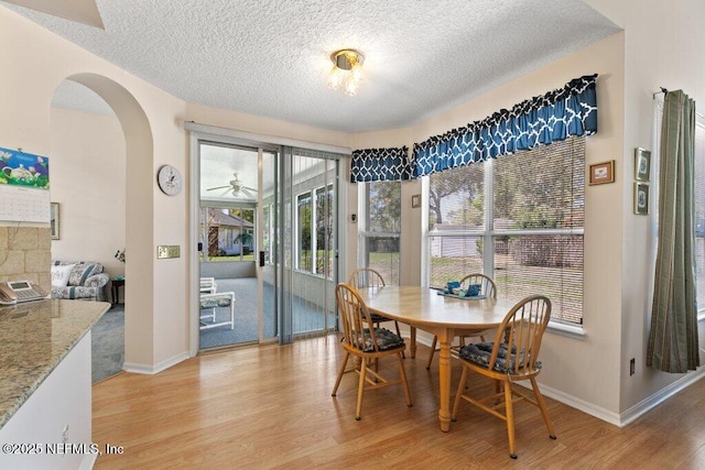 388 Lolly Ln, Saint Johns, FL 32259 - dining area featuring light wood-type flooring, arched walkways, a textured ceiling, and baseboards