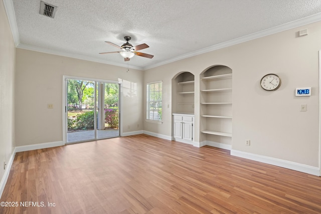 spare room with light wood-style flooring, a textured ceiling, built in shelves, visible vents, and a ceiling fan