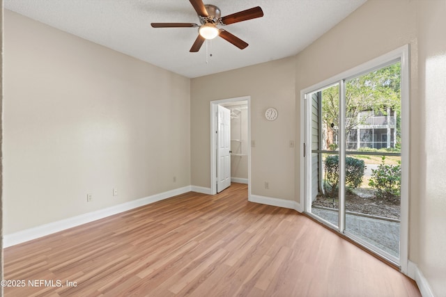 spare room featuring baseboards, light wood-type flooring, ceiling fan, and a textured ceiling