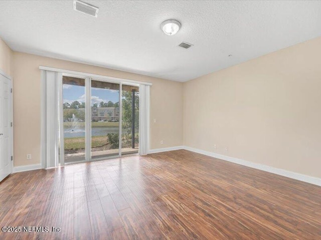 4442 Capital Dome Dr, Jacksonville, FL 32246 - unfurnished room with visible vents, a textured ceiling, baseboards, and wood finished floors