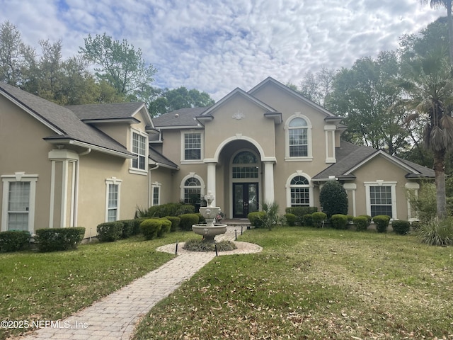 view of front facade with a front yard, stucco siding, and french doors