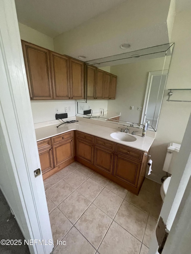 kitchen with light tile patterned flooring, brown cabinetry, light countertops, and a sink
