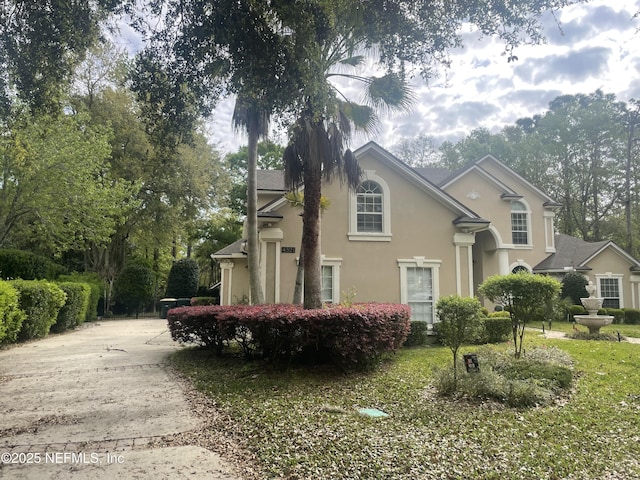 view of side of property featuring concrete driveway and stucco siding