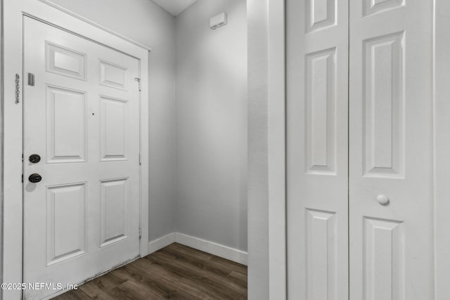 corridor featuring dark wood-type flooring and baseboards