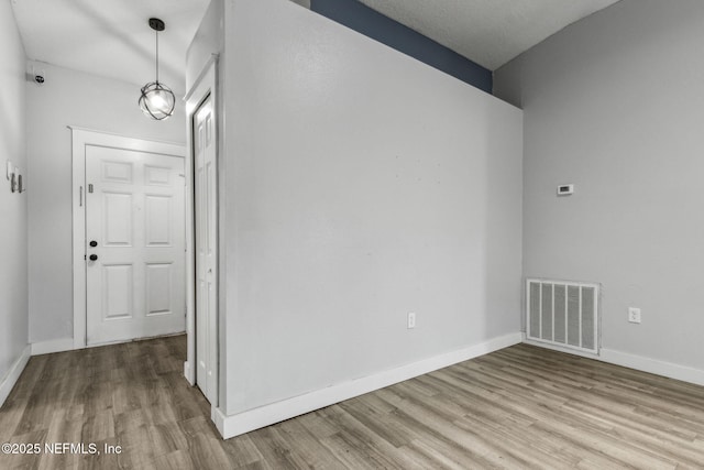spare room with wood finished floors, baseboards, and visible vents