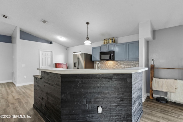 kitchen with stainless steel fridge, light wood-style floors, black microwave, and visible vents