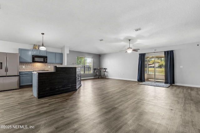 unfurnished living room with plenty of natural light, visible vents, ceiling fan, and dark wood finished floors