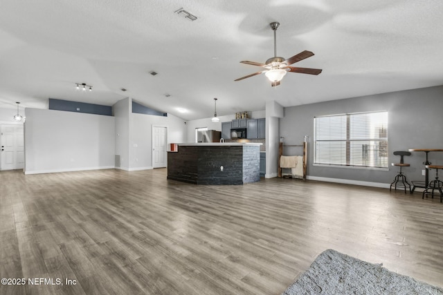 unfurnished living room with wood finished floors, baseboards, vaulted ceiling, and ceiling fan