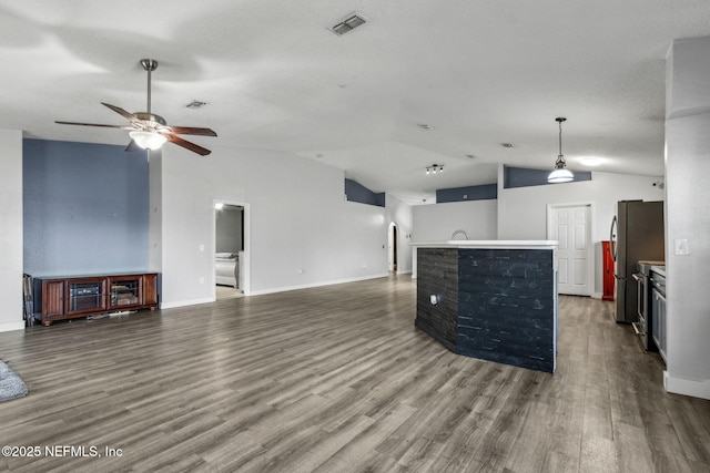 unfurnished living room with visible vents, ceiling fan, wood finished floors, and vaulted ceiling
