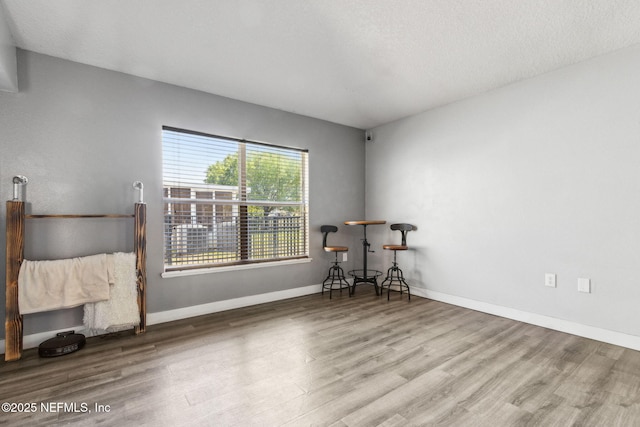 interior space featuring baseboards, a textured ceiling, and wood finished floors