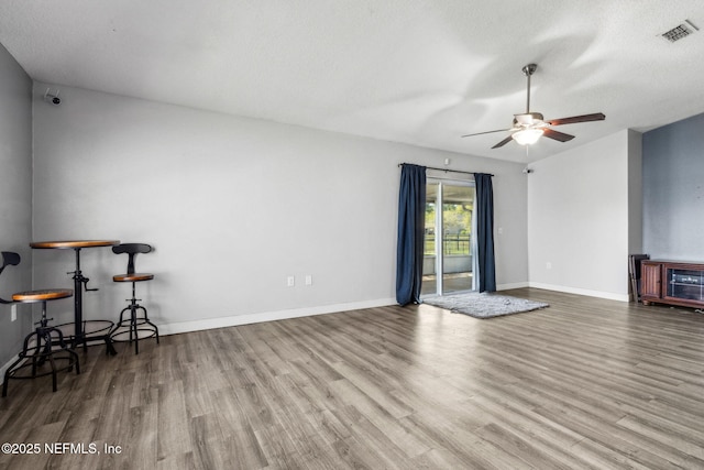 living area with wood finished floors, baseboards, ceiling fan, and visible vents