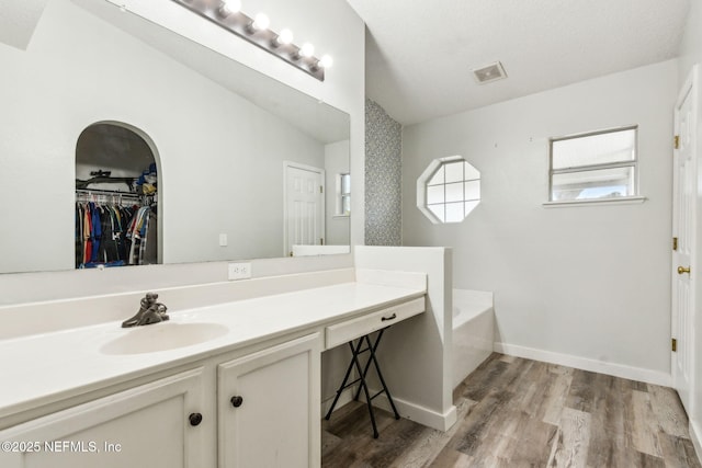 full bath featuring a bath, visible vents, wood finished floors, vanity, and vaulted ceiling