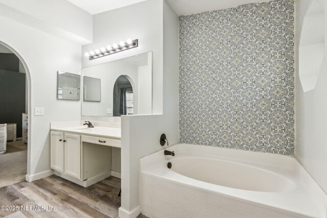 bathroom featuring wood finished floors, vanity, and a garden tub