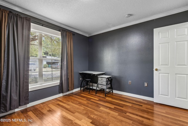 interior space with baseboards, a textured ceiling, wood finished floors, and crown molding