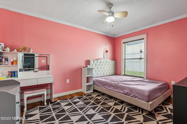 bedroom with a textured ceiling, baseboards, ornamental molding, wood finished floors, and ceiling fan
