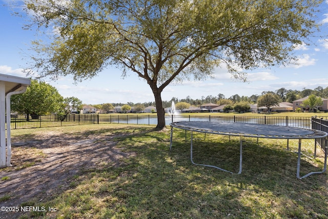 view of yard with a water view, fence, and a trampoline