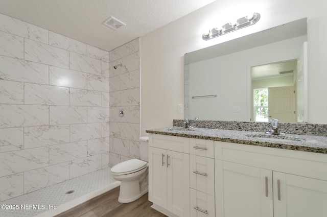 5755 Teeler Ave, Jacksonville, FL 32208 - bathroom featuring tiled shower, toilet, wood finished floors, and double vanity
