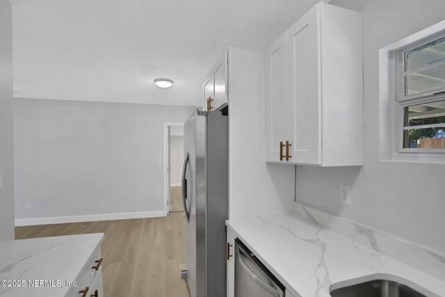 5517 Graywood Rd, Jacksonville, FL 32207 - kitchen with white cabinetry, stainless steel appliances, baseboards, light wood-style floors, and light stone counters